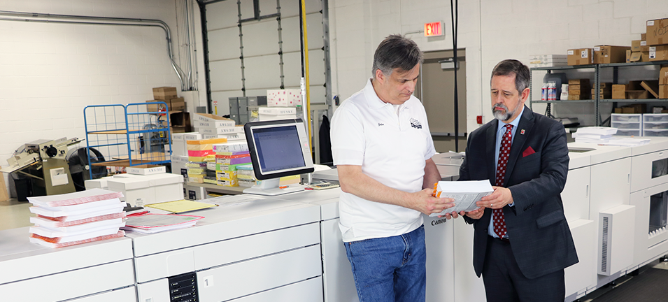 3-knife trimmer operator John Ruder and President Steve Johnson inspect the book print quality before shipping.
